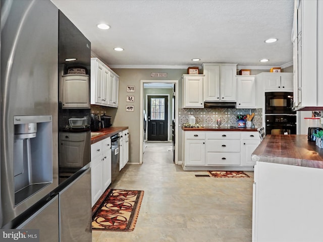 kitchen with wood counters, crown molding, black appliances, white cabinetry, and backsplash