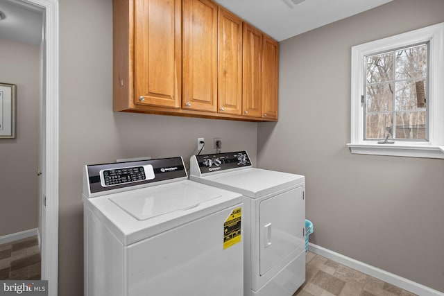 laundry area featuring washing machine and dryer, cabinet space, and baseboards