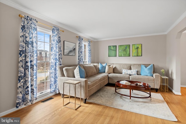 living room with light wood-style floors, visible vents, ornamental molding, and baseboards