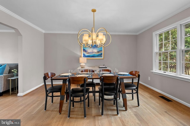 dining space featuring a chandelier, arched walkways, visible vents, light wood-type flooring, and a wealth of natural light