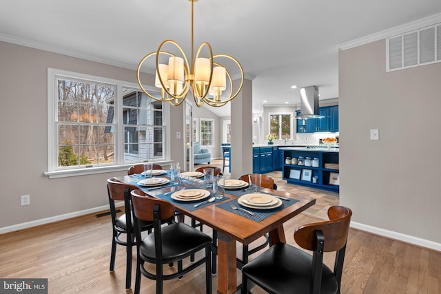 dining area featuring light wood-type flooring, an inviting chandelier, visible vents, and crown molding