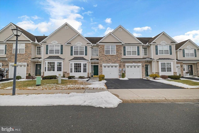 view of property with a garage, driveway, and stone siding