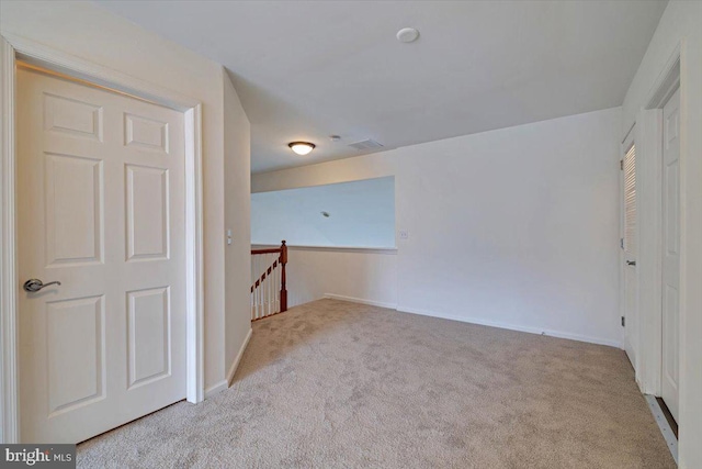 spare room with light colored carpet, visible vents, and baseboards