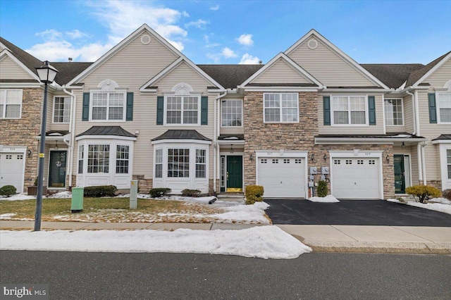 multi unit property with driveway, stone siding, and an attached garage