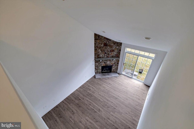 unfurnished living room with lofted ceiling, a fireplace, and wood finished floors