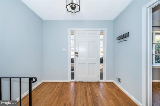 foyer entrance with baseboards, plenty of natural light, visible vents, and wood finished floors