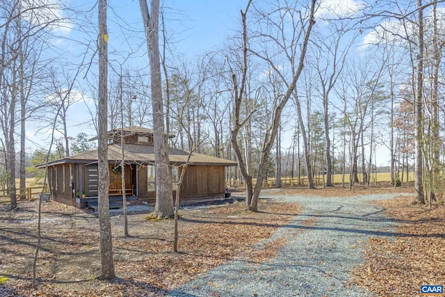 view of side of home with a sunroom, roof with shingles, and driveway