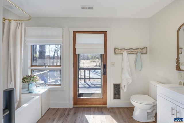 bathroom with toilet, baseboards, vanity, wood finished floors, and visible vents