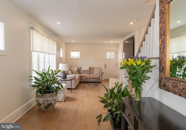 living area featuring light wood-type flooring, recessed lighting, stairs, and baseboards