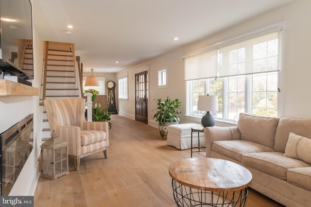 living room featuring light wood finished floors, recessed lighting, baseboards, and stairs