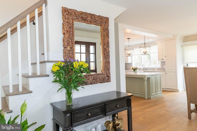 hallway with light wood-style flooring, stairway, and a sink