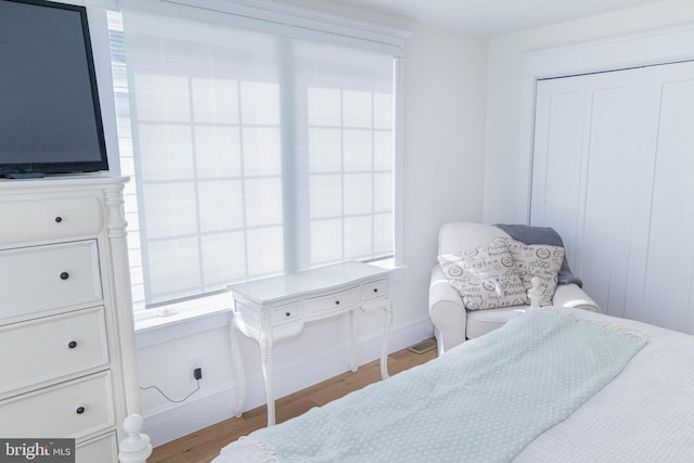 bedroom featuring light wood-style flooring, baseboards, and a closet