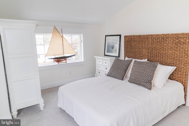 bedroom featuring light carpet, baseboards, and lofted ceiling