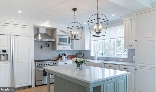 kitchen featuring wall chimney exhaust hood, stainless steel appliances, a center island, and white cabinetry