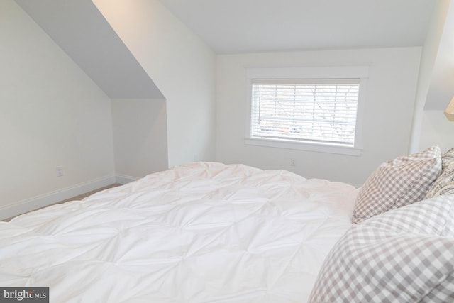 bedroom with vaulted ceiling and baseboards