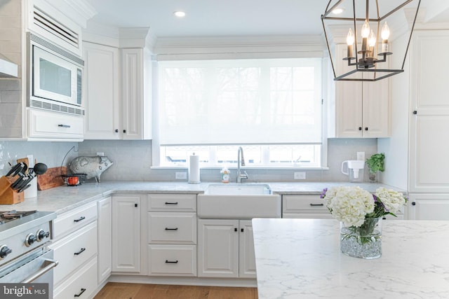 kitchen with plenty of natural light, stainless steel appliances, white cabinetry, and a sink