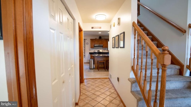 hallway featuring light tile patterned flooring and stairs