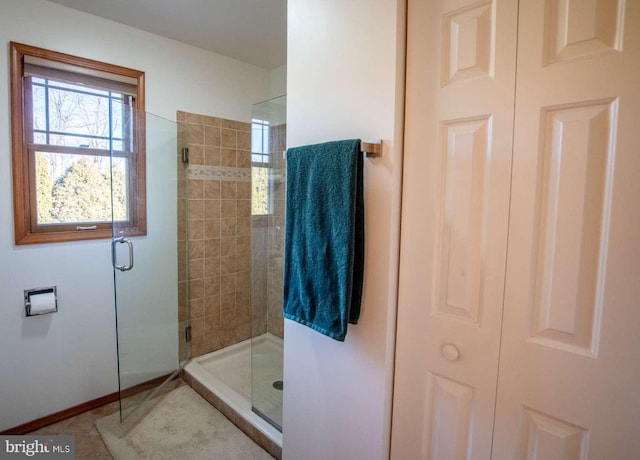 bathroom with a stall shower, baseboards, a closet, and tile patterned flooring