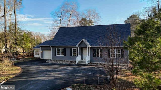 cape cod home with aphalt driveway, an attached garage, and a shingled roof