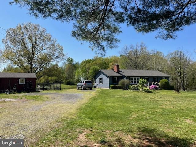 view of side of home featuring a yard, a chimney, and driveway