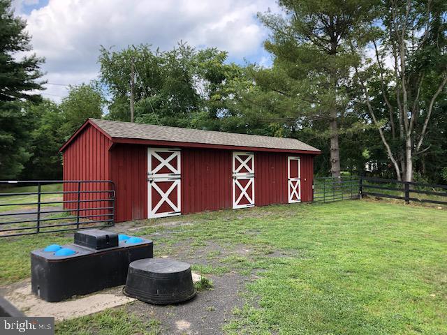 view of barn featuring a lawn and fence