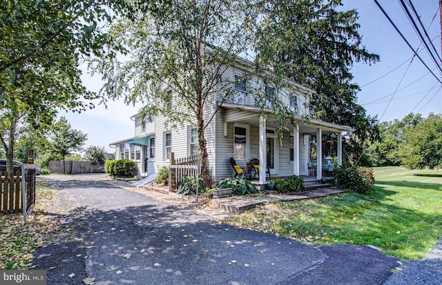 view of front of house with driveway, covered porch, and fence