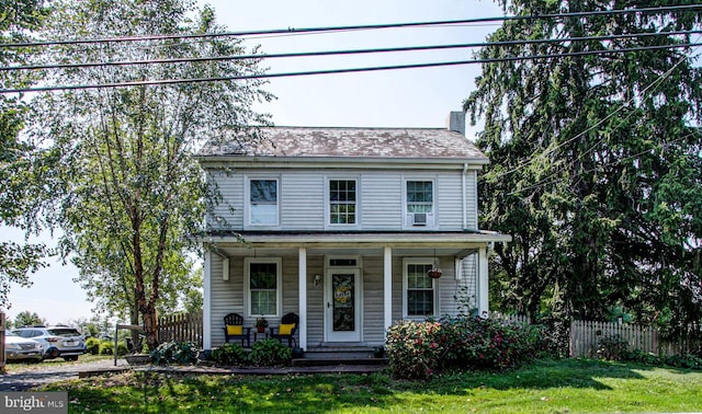 view of front of home with a chimney, fence, a front lawn, and a porch