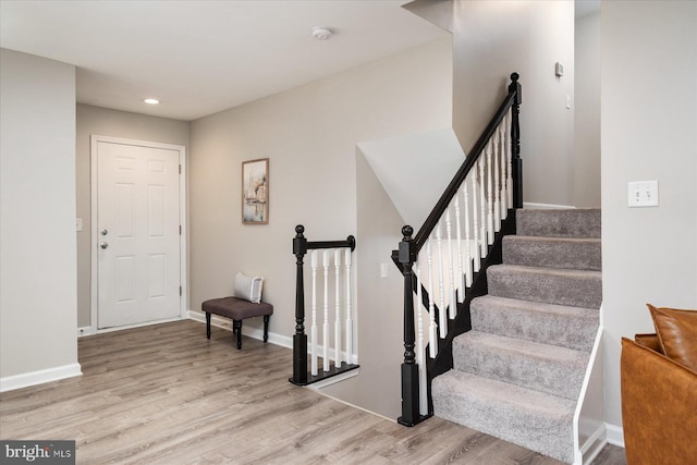 stairway with wood finished floors, baseboards, and recessed lighting