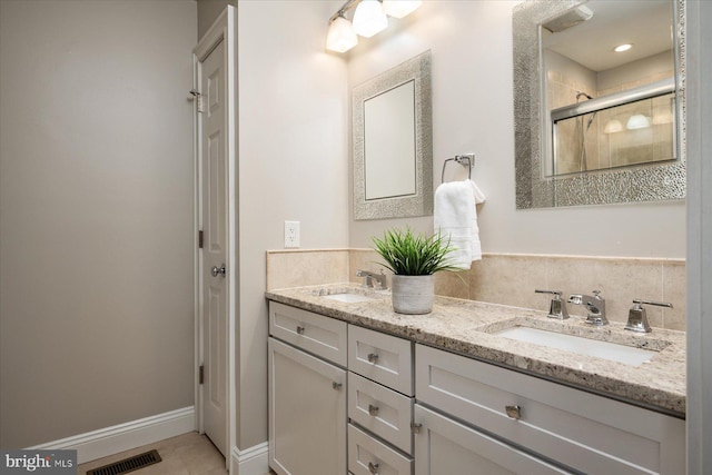 full bath featuring double vanity, visible vents, a shower stall, and a sink