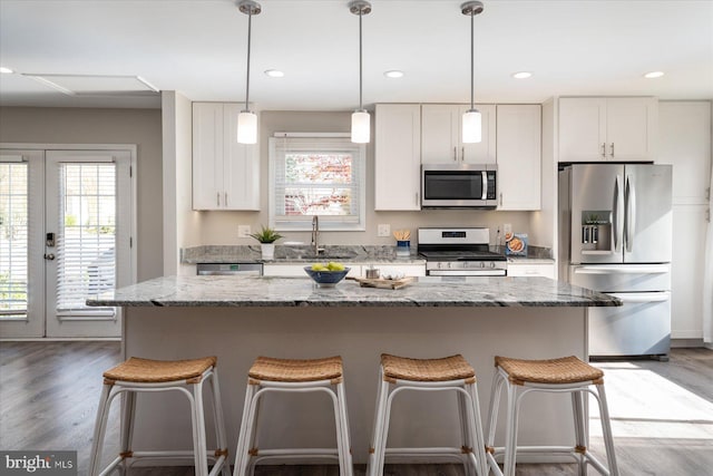 kitchen featuring appliances with stainless steel finishes, white cabinets, a kitchen island, and a sink