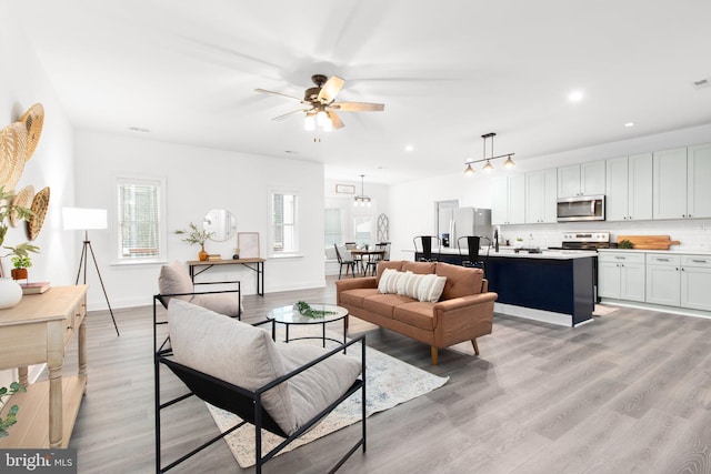 living area featuring baseboards, a ceiling fan, light wood finished floors, and recessed lighting