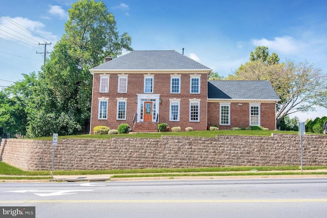 colonial-style house with brick siding and fence