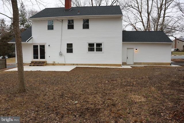 back of house featuring a shingled roof, entry steps, a patio, and a chimney