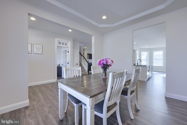 dining space with ornamental molding, light wood finished floors, and baseboards