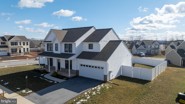 view of front of home with fence, a residential view, a shingled roof, aphalt driveway, and a front yard