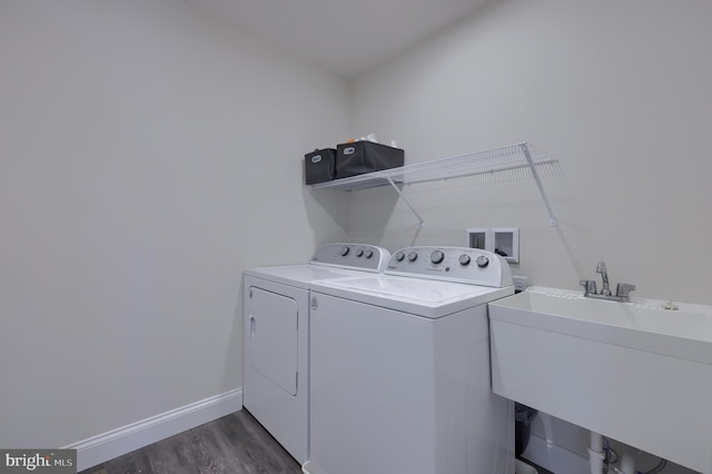 clothes washing area featuring baseboards, a sink, laundry area, independent washer and dryer, and dark wood-style floors