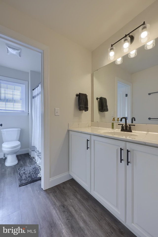 full bath featuring baseboards, visible vents, toilet, vanity, and wood finished floors