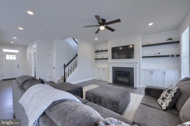 living area featuring dark wood finished floors, stairs, recessed lighting, and a glass covered fireplace