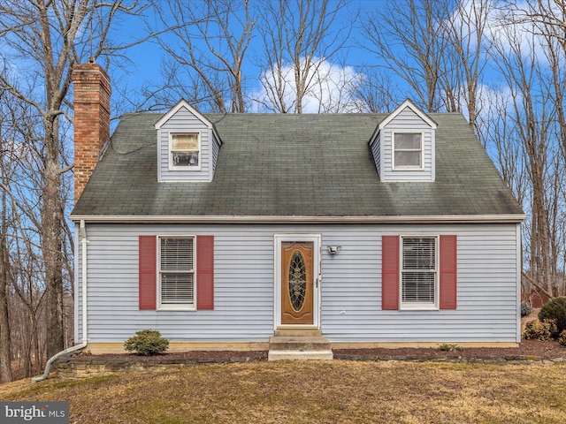 cape cod house featuring entry steps, a chimney, and a front yard