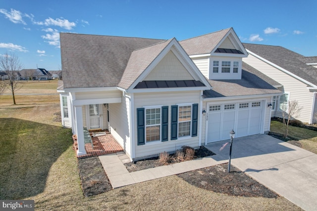 view of front of home with metal roof, an attached garage, concrete driveway, a front lawn, and a standing seam roof