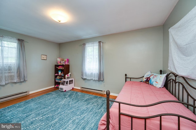 bedroom with a baseboard radiator, wood finished floors, and multiple windows