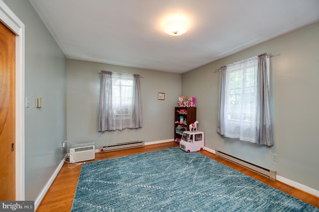 playroom featuring baseboards, an AC wall unit, baseboard heating, and wood finished floors