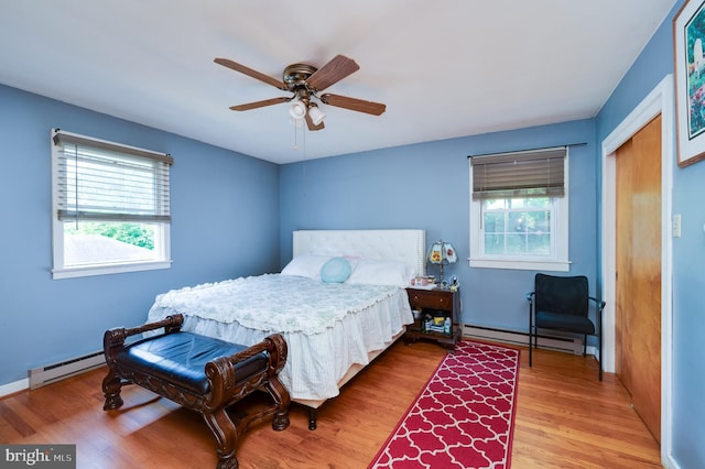 bedroom featuring a baseboard heating unit, light wood-style flooring, a closet, and ceiling fan