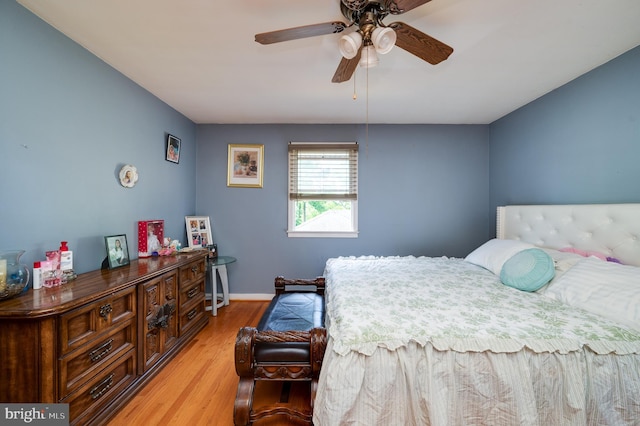 bedroom with a ceiling fan, baseboards, and light wood-style floors