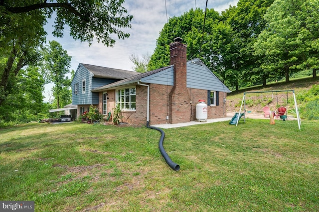 view of side of property with brick siding, a chimney, and a yard