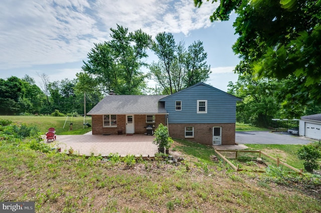 back of house featuring a patio area, driveway, a garage, a yard, and brick siding