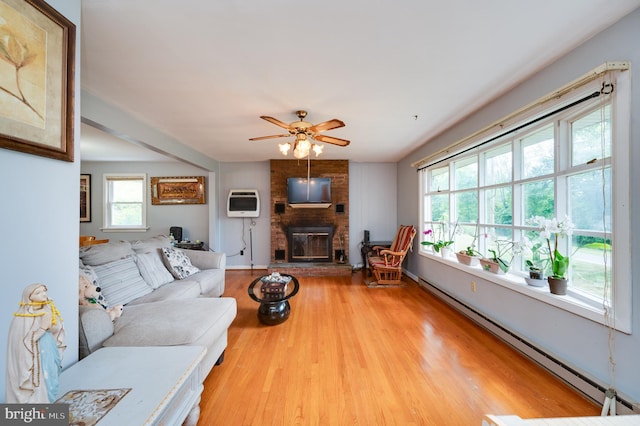 living room with a ceiling fan, baseboards, baseboard heating, light wood-style floors, and a fireplace