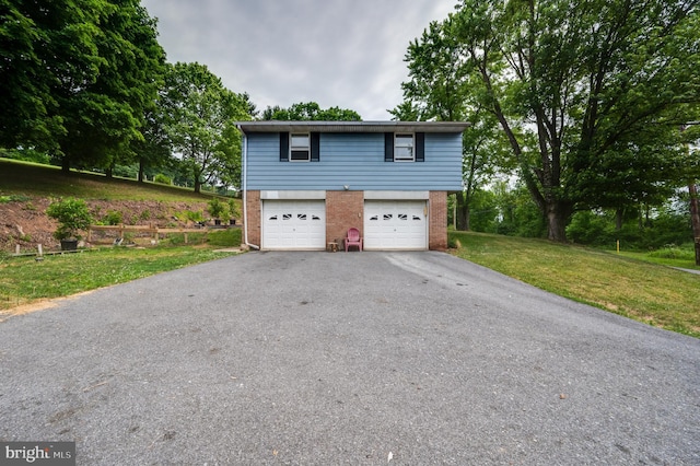 view of front facade with a front yard, aphalt driveway, a garage, and brick siding