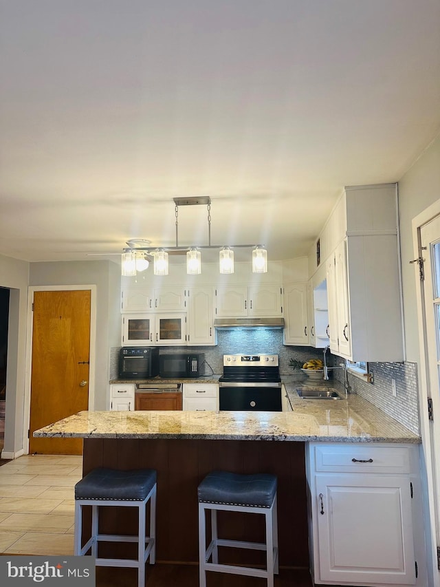 kitchen with a breakfast bar area, white cabinets, electric stove, a peninsula, and a sink