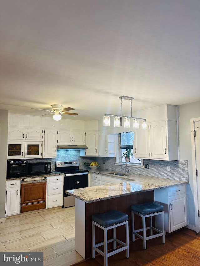 kitchen with stainless steel range with electric stovetop, white cabinetry, a sink, and black microwave